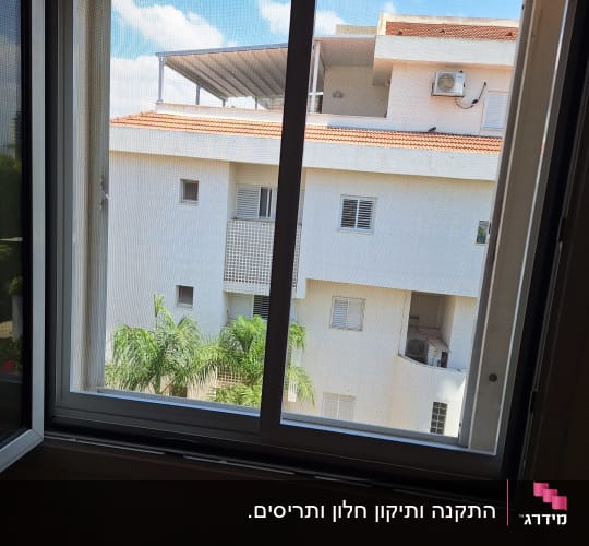 חלון אלומיניום פתוח עם נוף לבניין סמוך